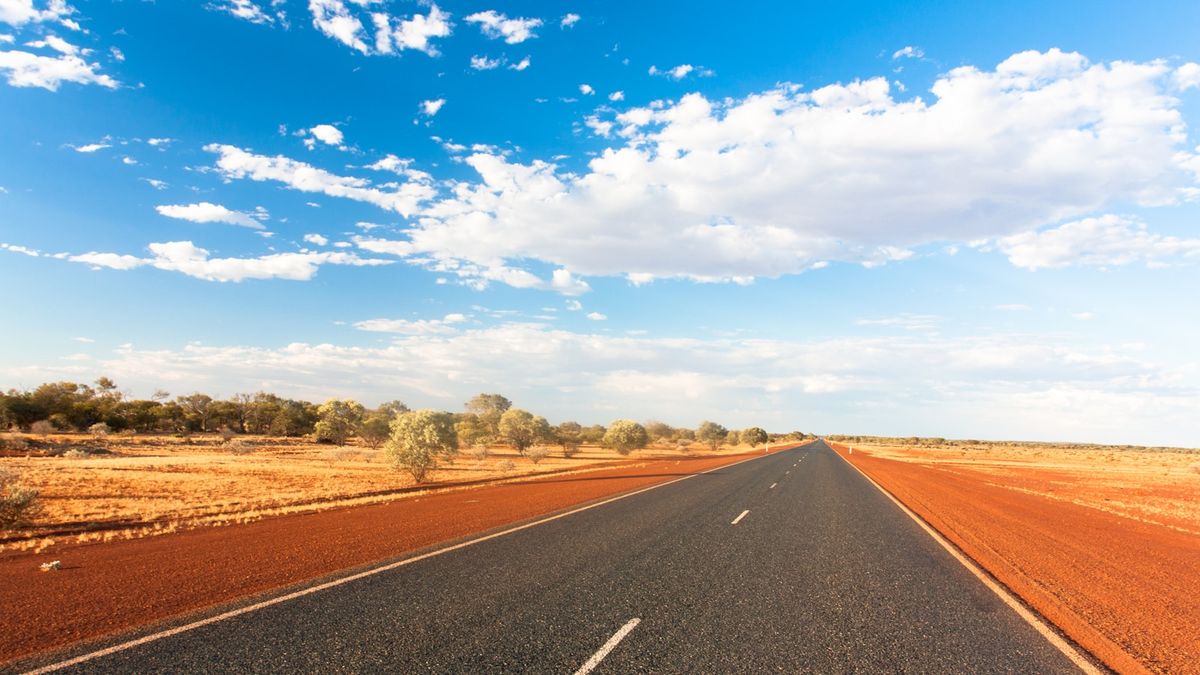 Long straight road through the Australian outback under blue sky