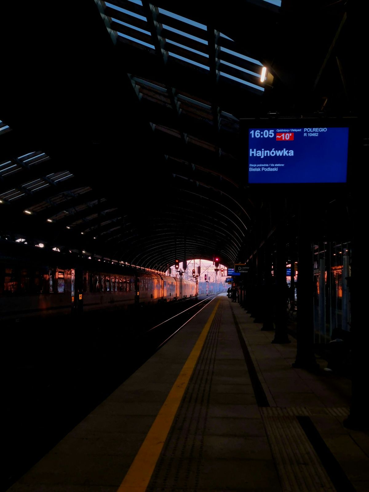 Train station platform at dusk with departure board