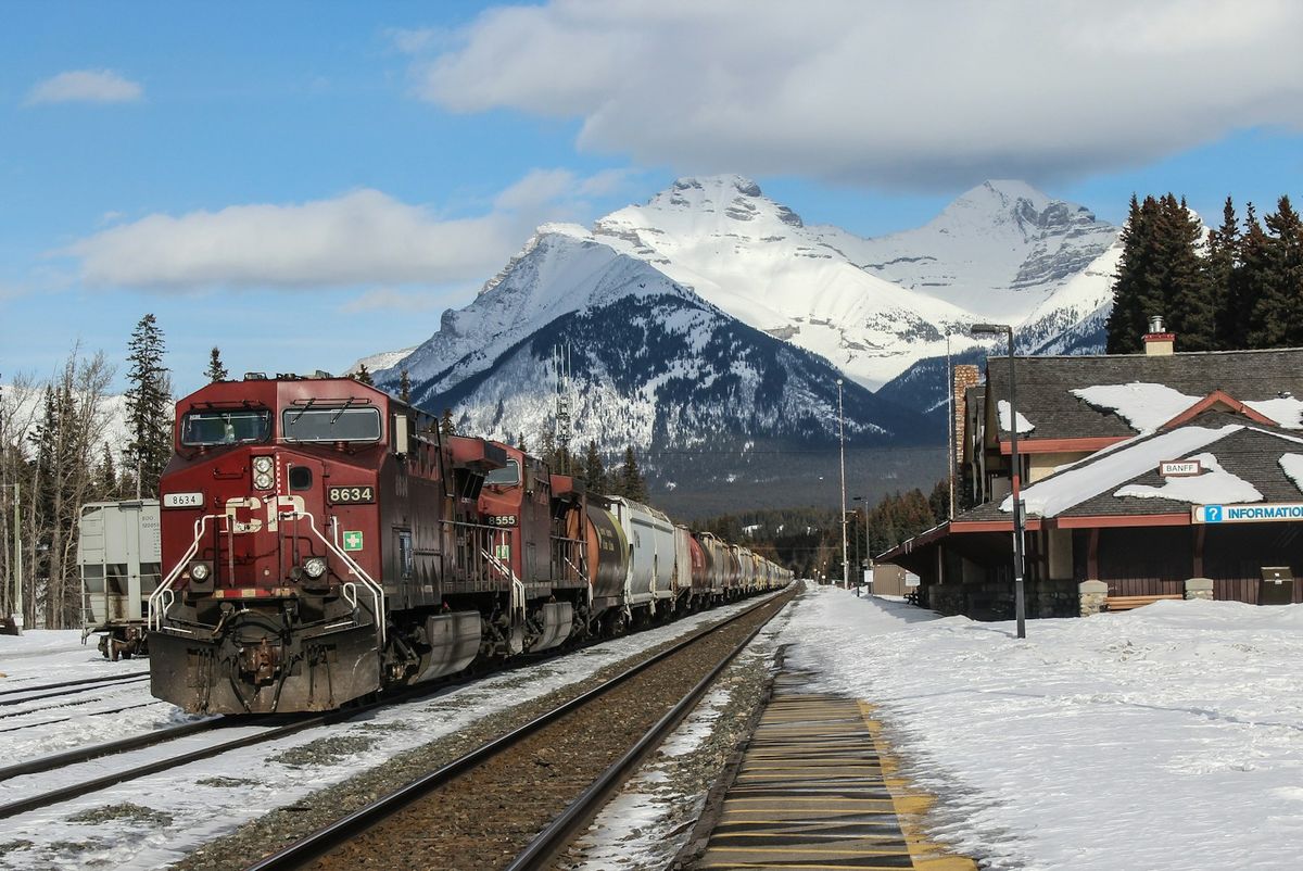 Red passenger train through snow-covered mountains in Canadian Rockies