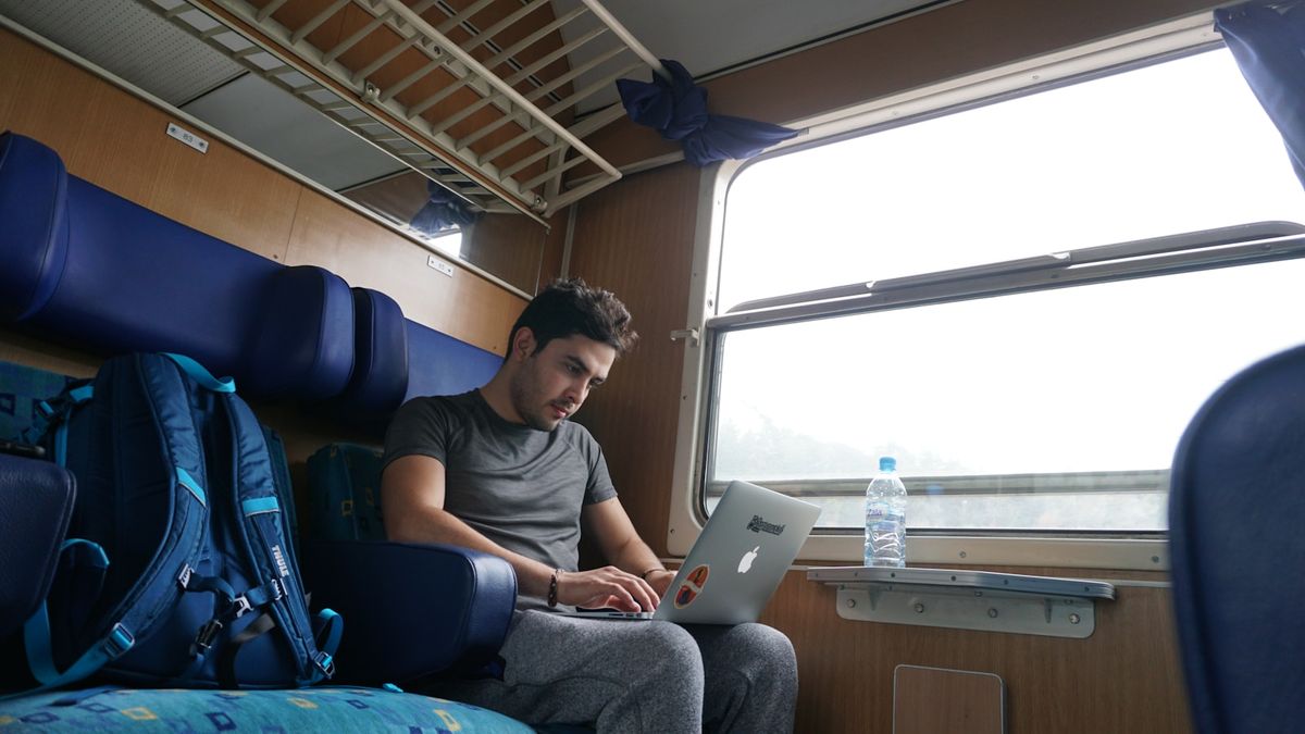 Laptop in use on a train table by the window