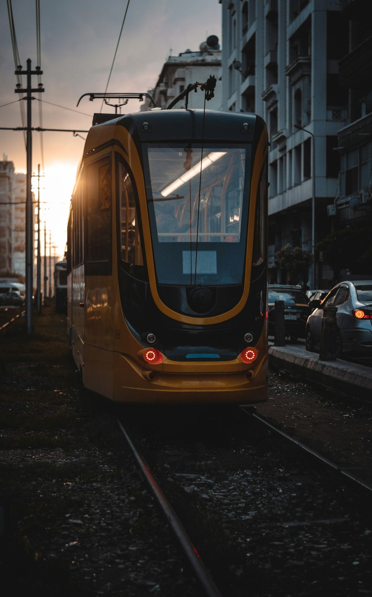 A yellow Egyptian train on the tracks by the city