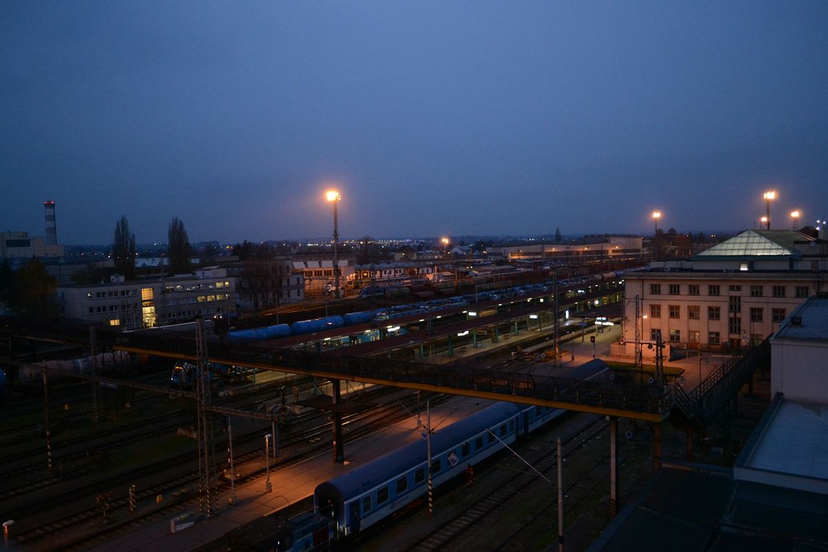 Illuminated train station at dusk with tracks and platforms