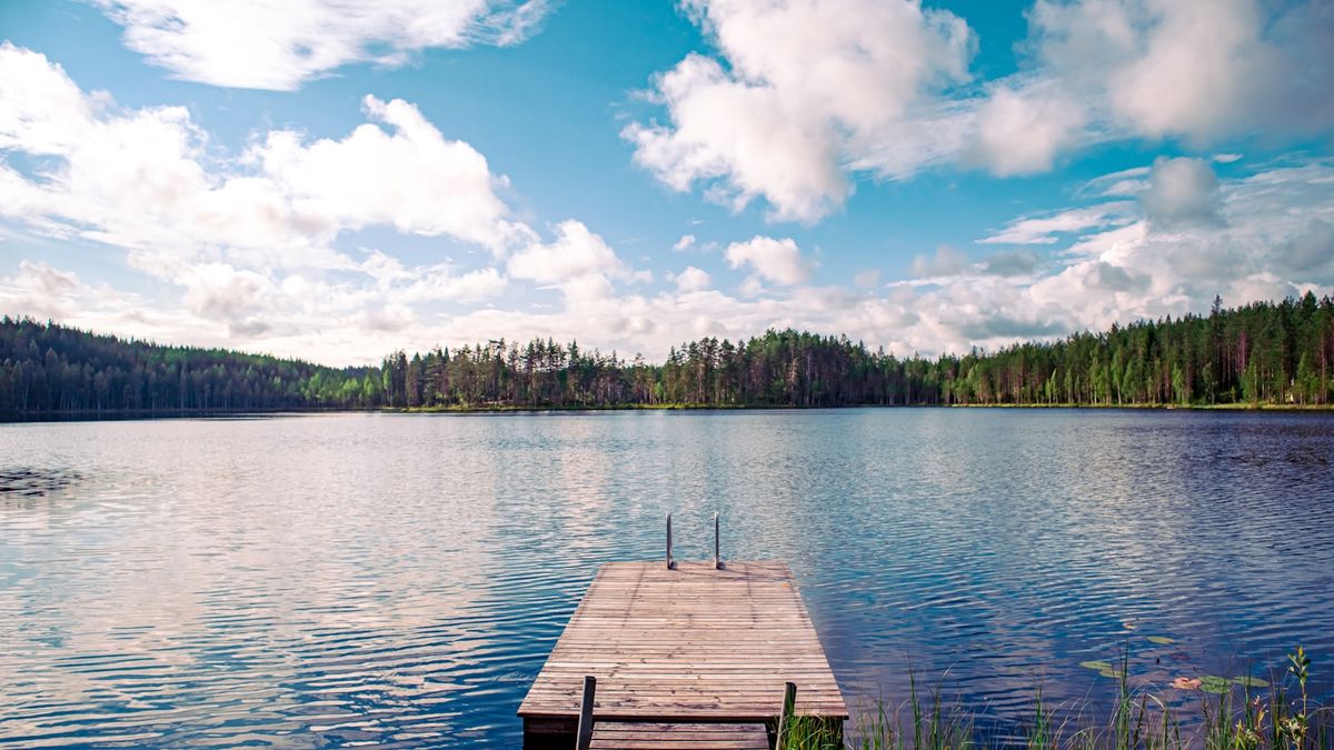 Wooden dock extending into calm Finnish lake in summer