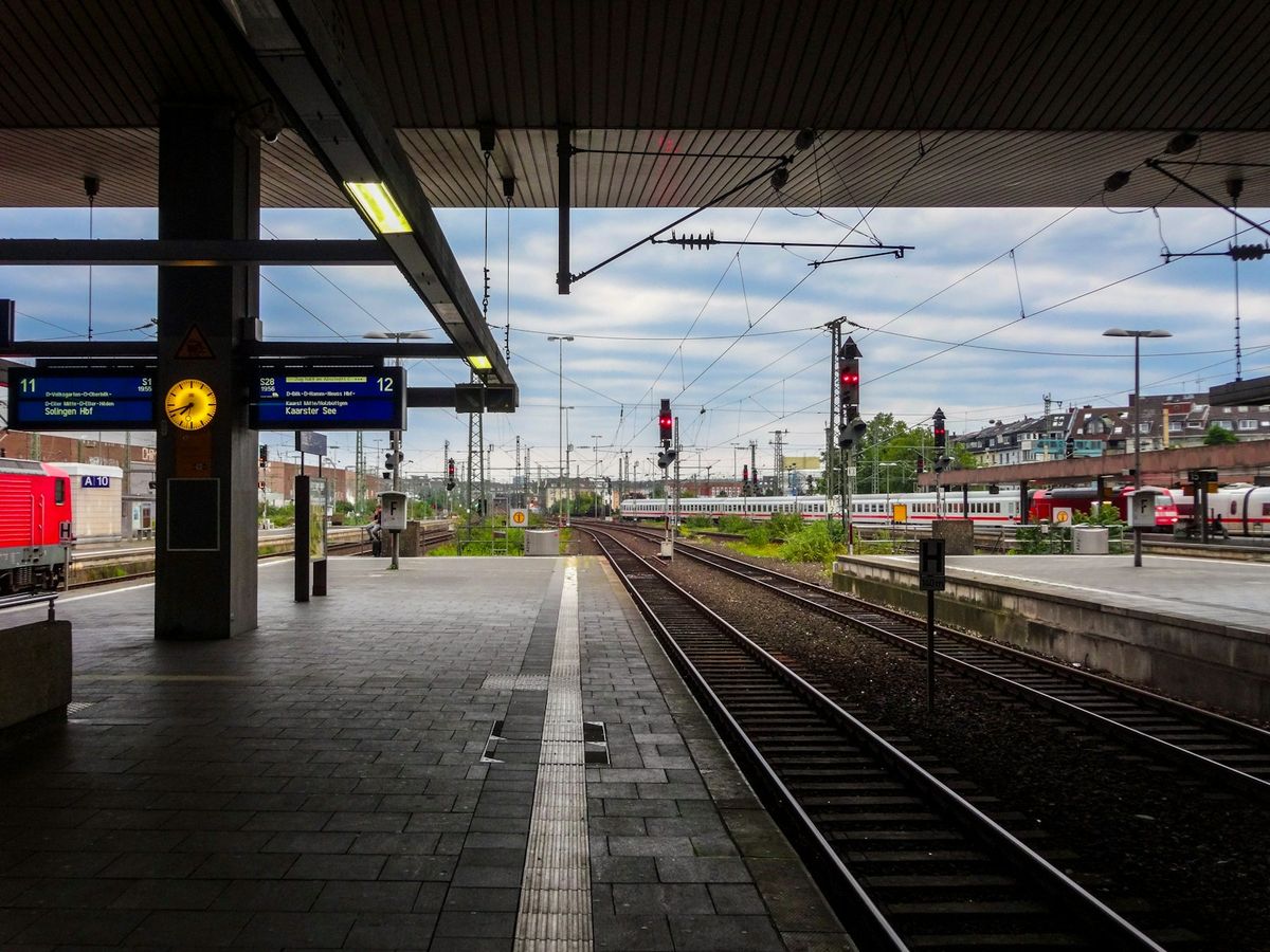 European train station platform with tracks and overhead wires