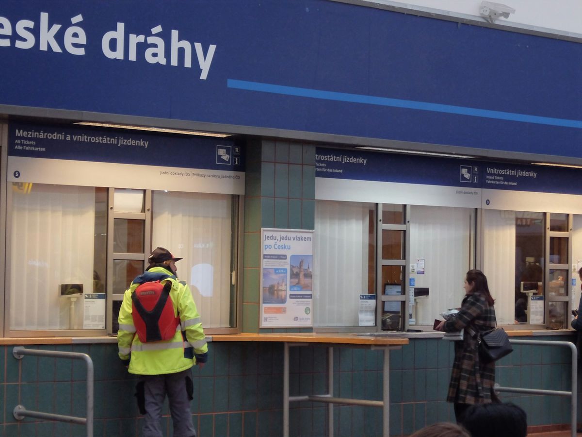Passengers at a train station ticket counter buying tickets