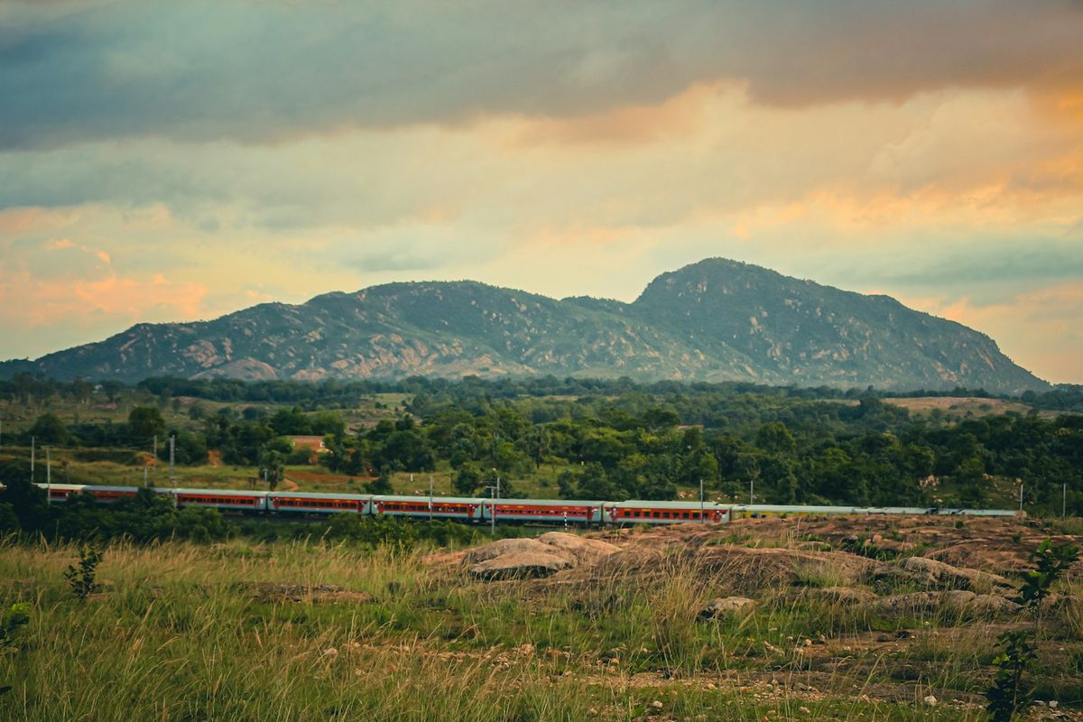 Train traveling through rolling hills and mountains in India