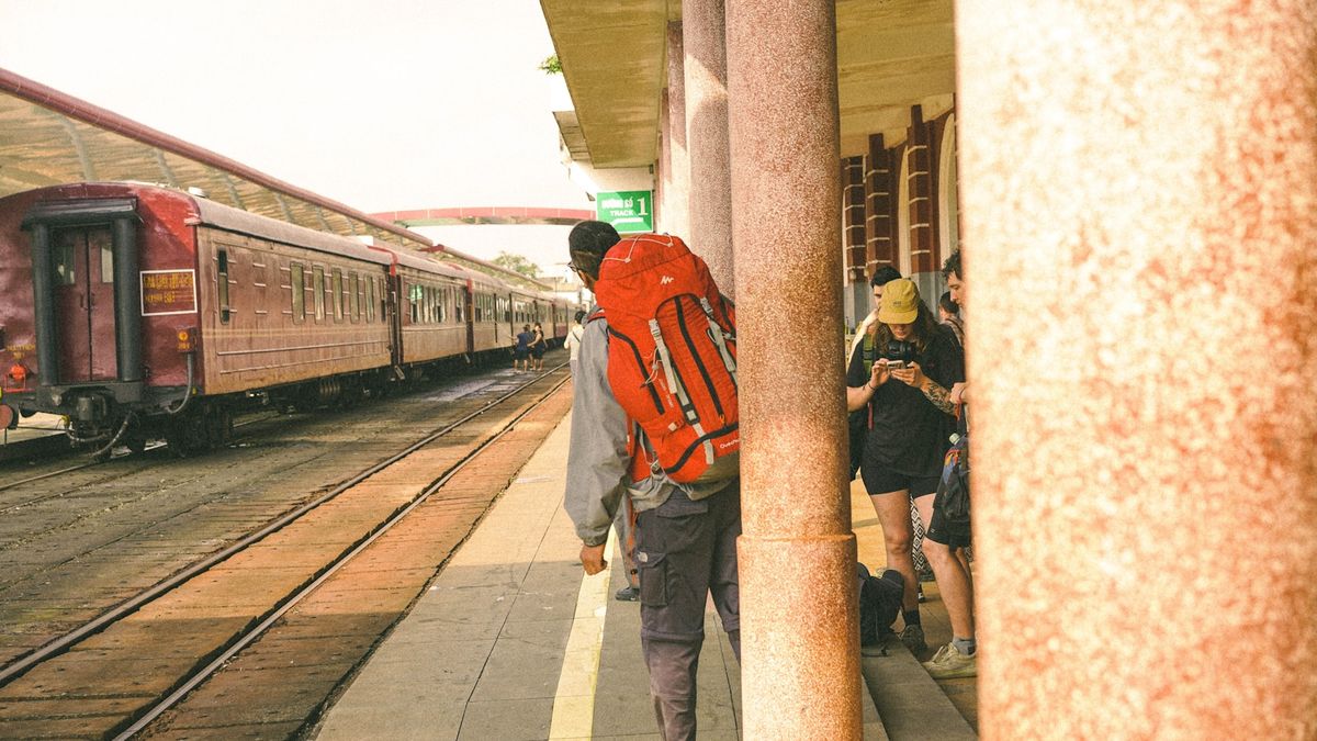 Man with red backpack waiting at train station platform