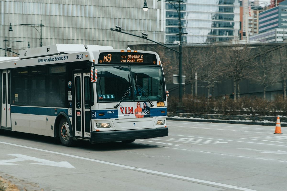 White and blue transit bus on road as rail replacement service