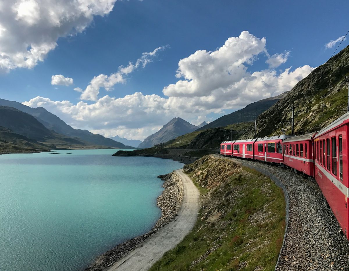 Red Swiss train travelling near a mountain lake