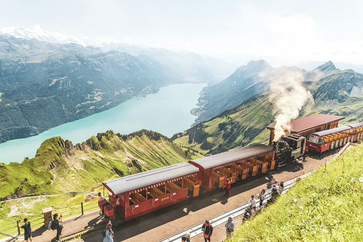 Red train passing a green hillside in the Swiss Alps