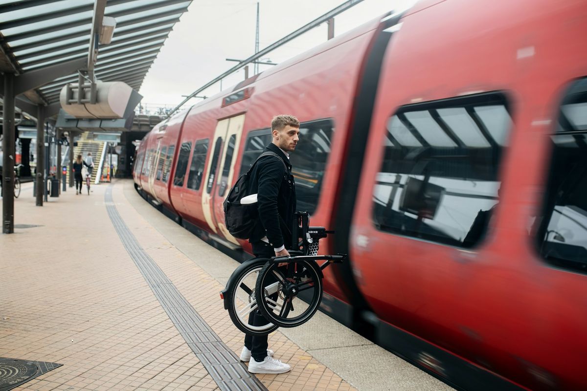 Man holding a bicycle beside a train