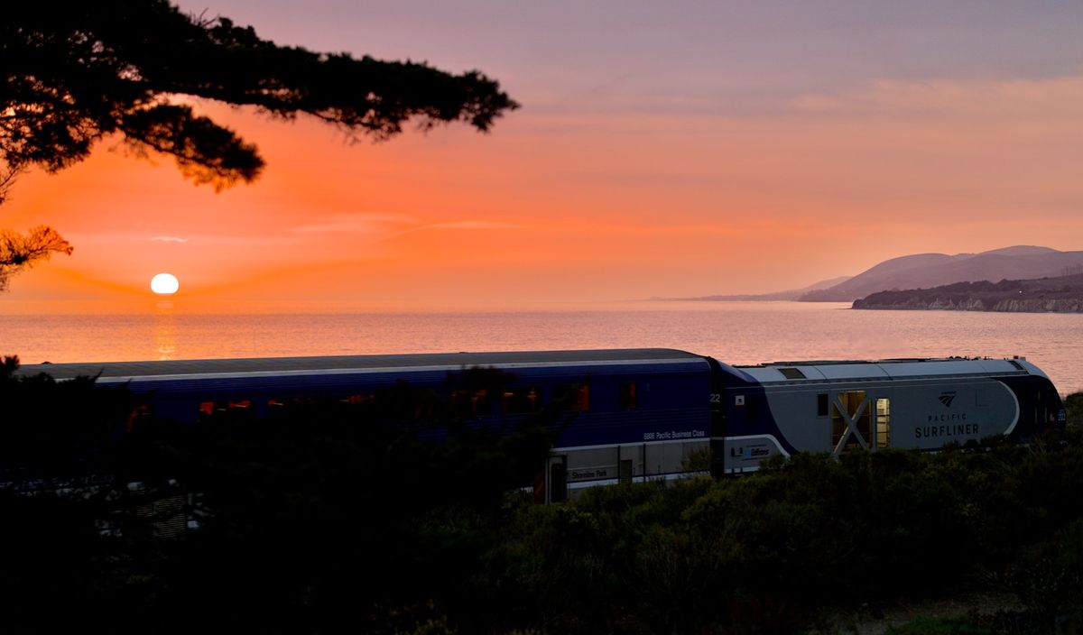 Passenger train departing during a coastal sunset