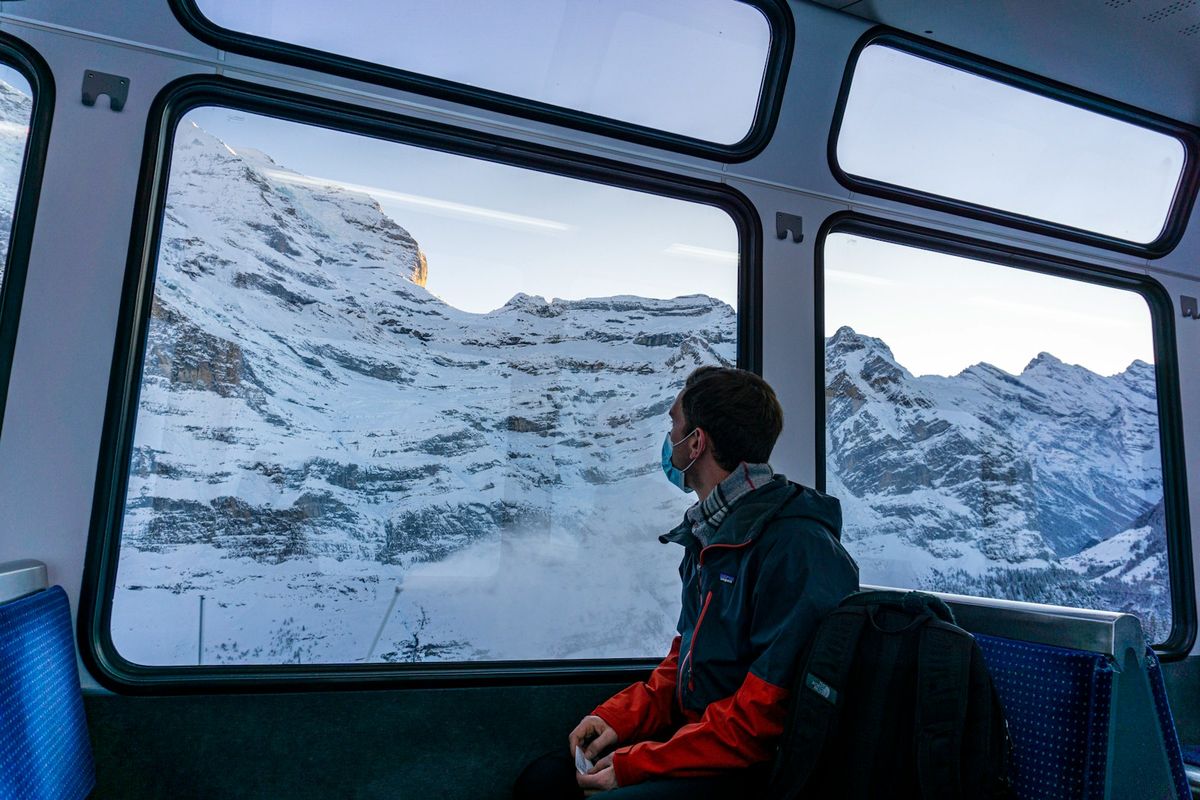 Passenger looking out a train window at snow-covered Alps on the way to Jungfraujoch