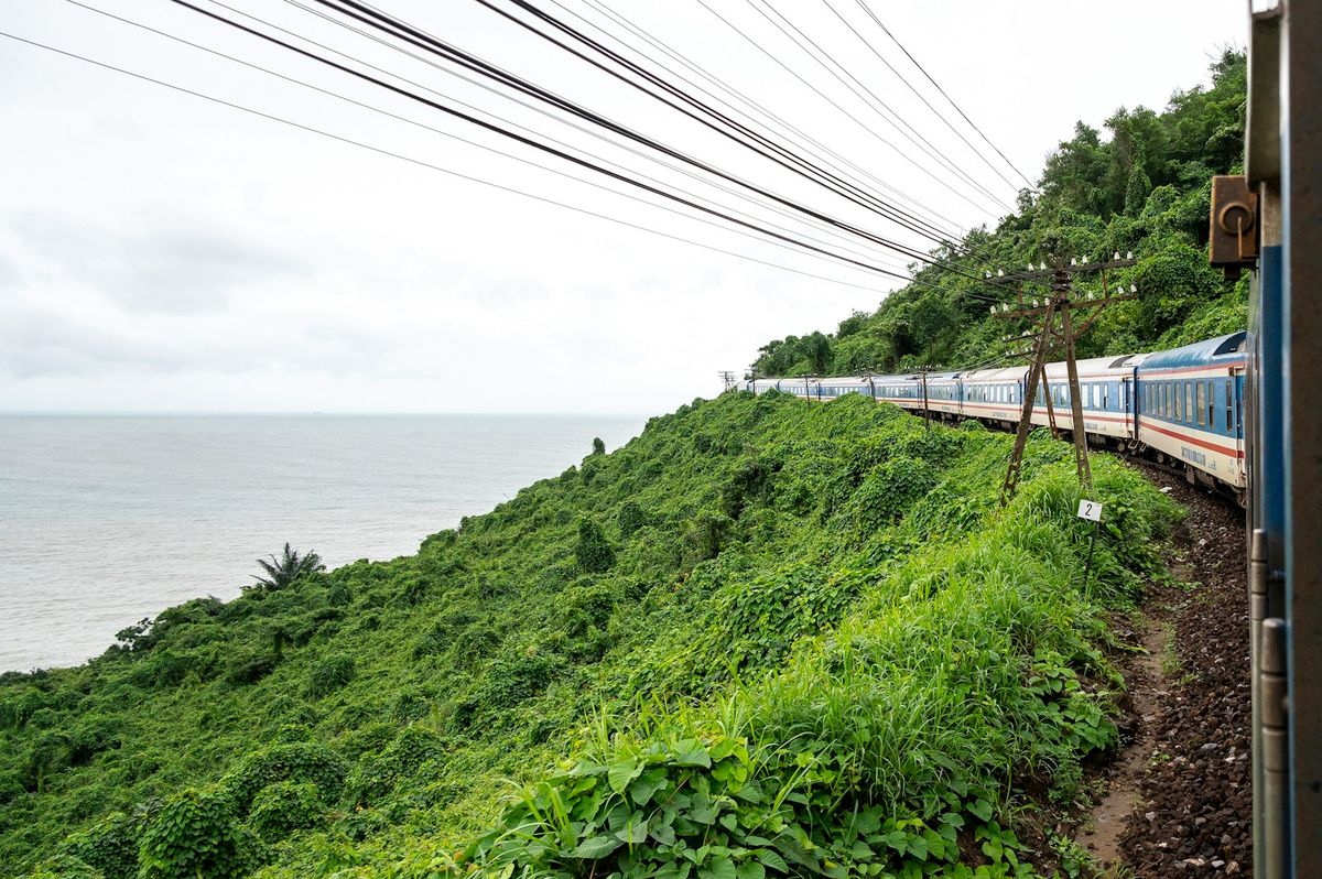 Train travelling along a scenic hillside track in Vietnam