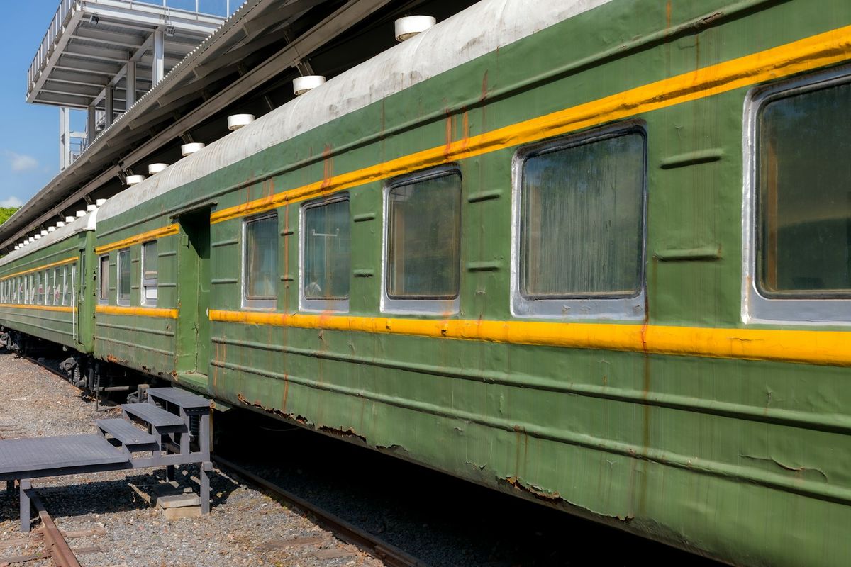 Green train carriages with yellow stripes at a station