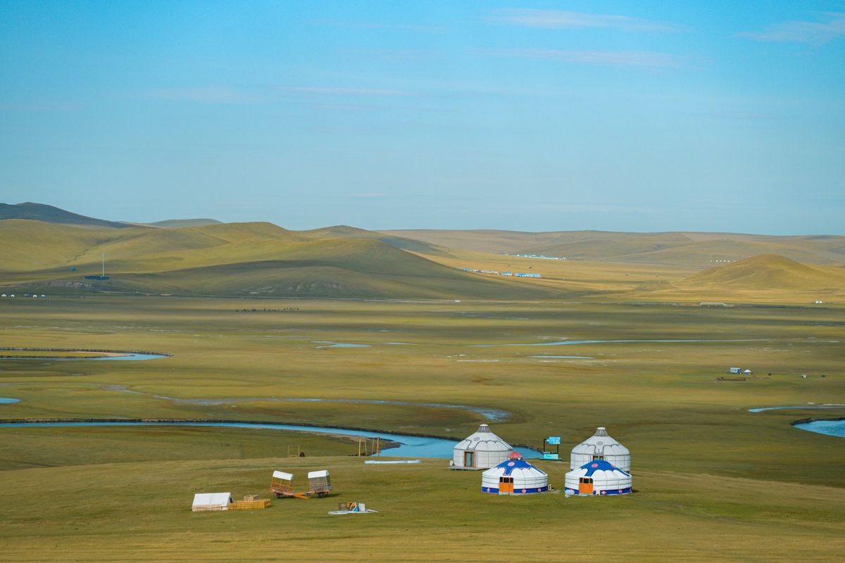 Traditional yurts on the vast Mongolian steppe under blue sky