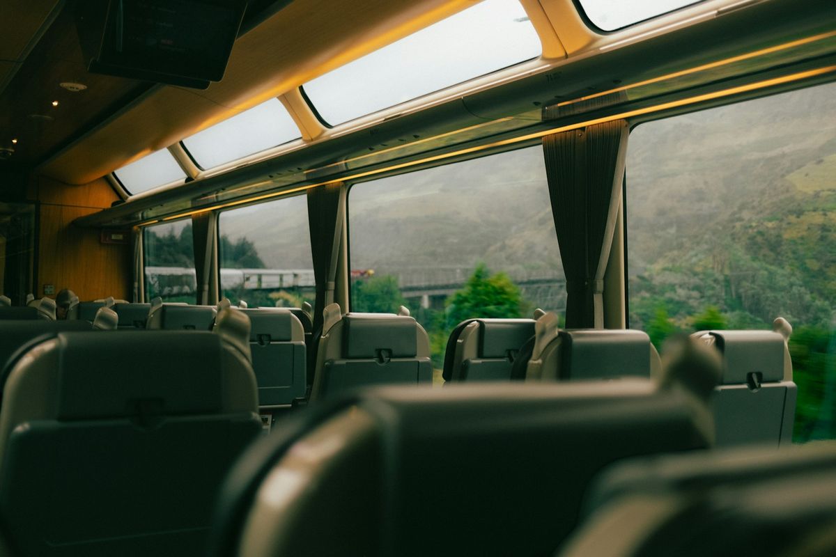 Train carriage window with green mountain scenery in New Zealand