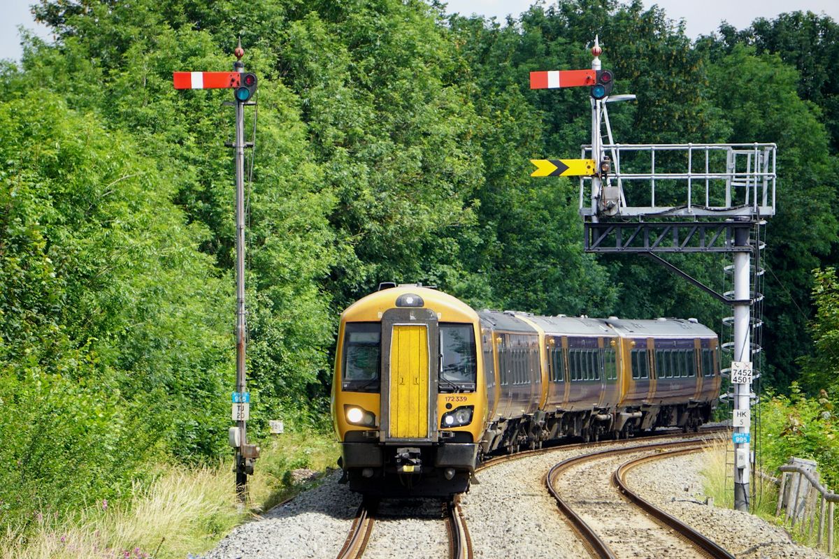 Yellow British train travelling through green countryside