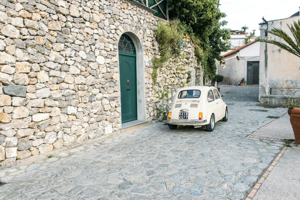Vintage cream car parked on a narrow European cobblestone street