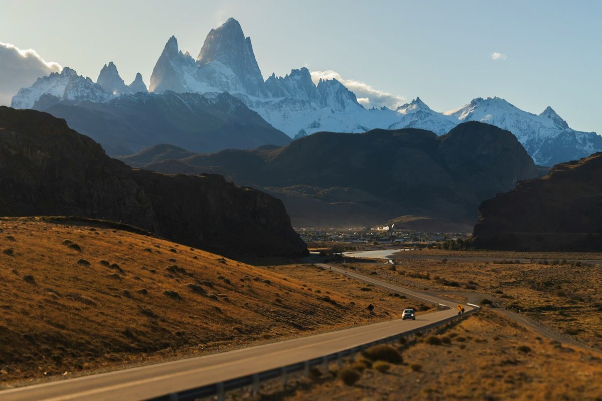 A car driving down a remote Patagonian road with distant mountains