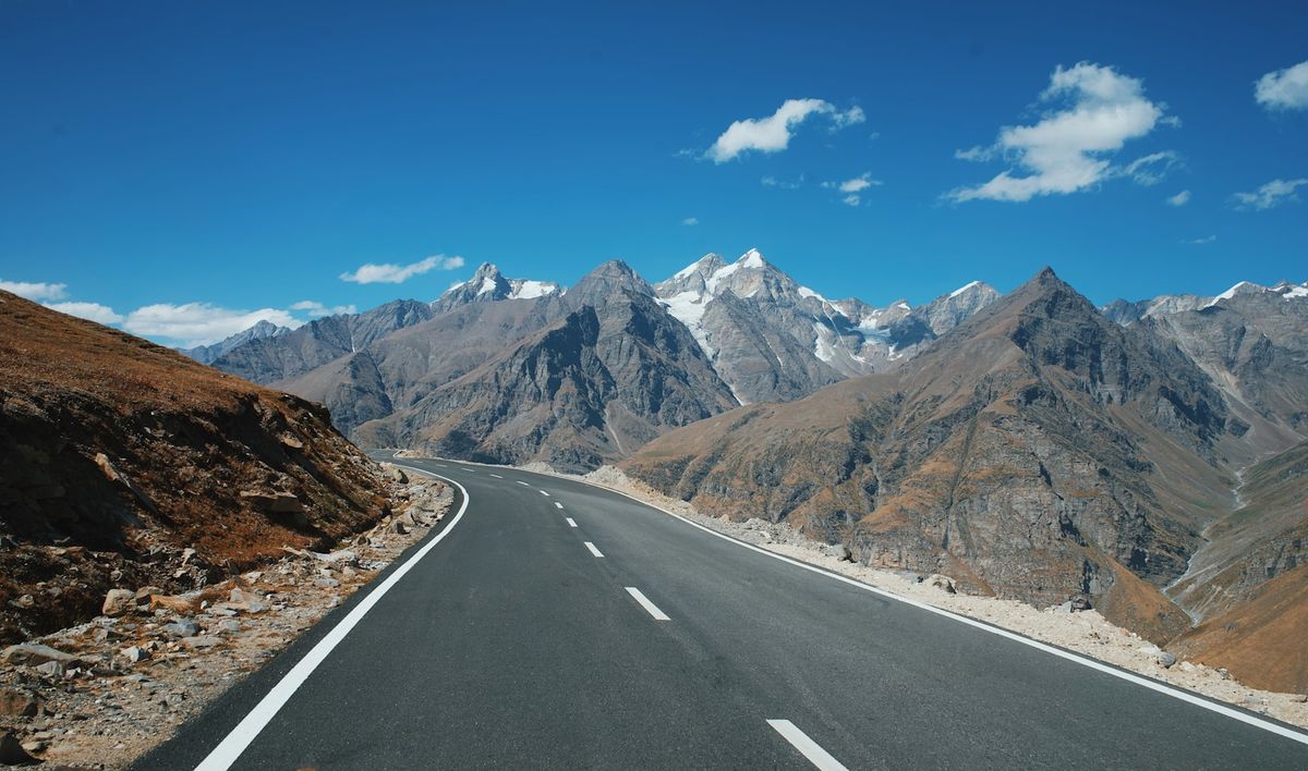 Gray concrete road along rocky brown mountains in India