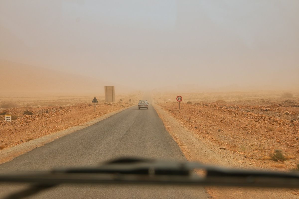 Empty road through brown sand desert in Morocco