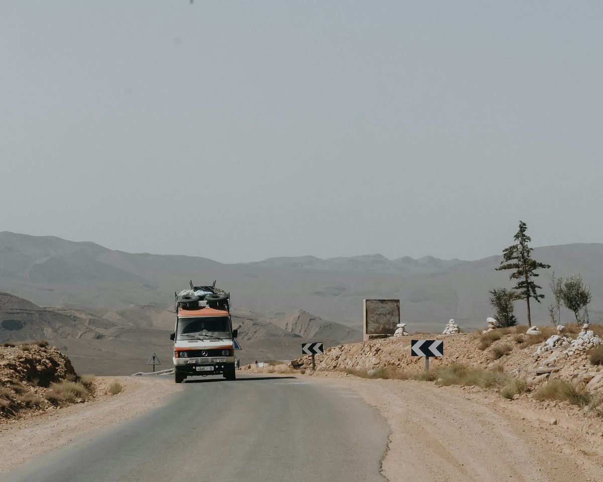 Truck on dusty desert road with Atlas Mountains in background