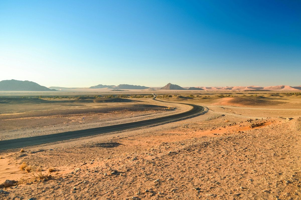 An isolated straight gravel road stretching through the Namibian desert