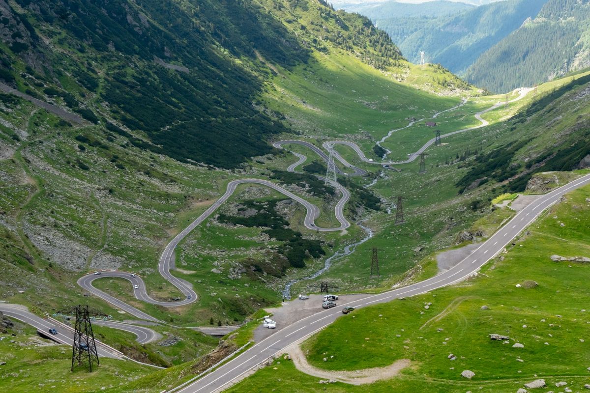 Winding mountain road through a lush green Carpathian valley in Romania