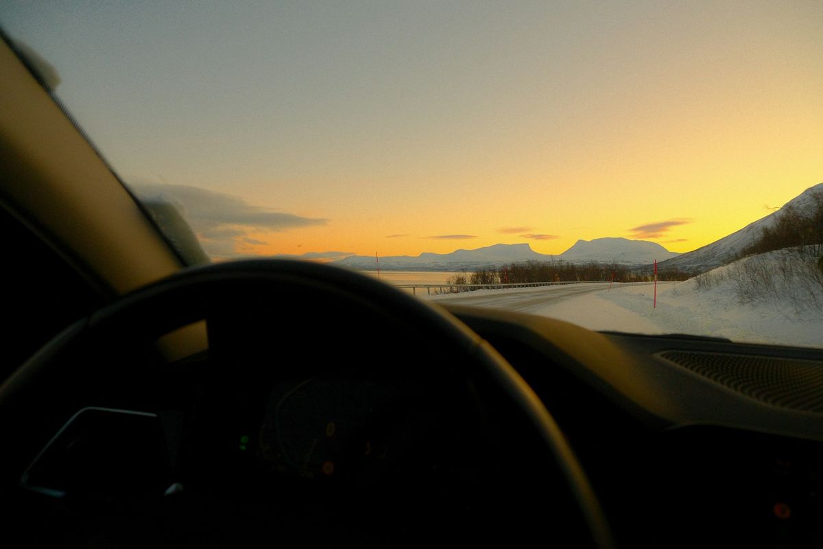 Driving towards snowy mountain landscape at sunset in Sweden