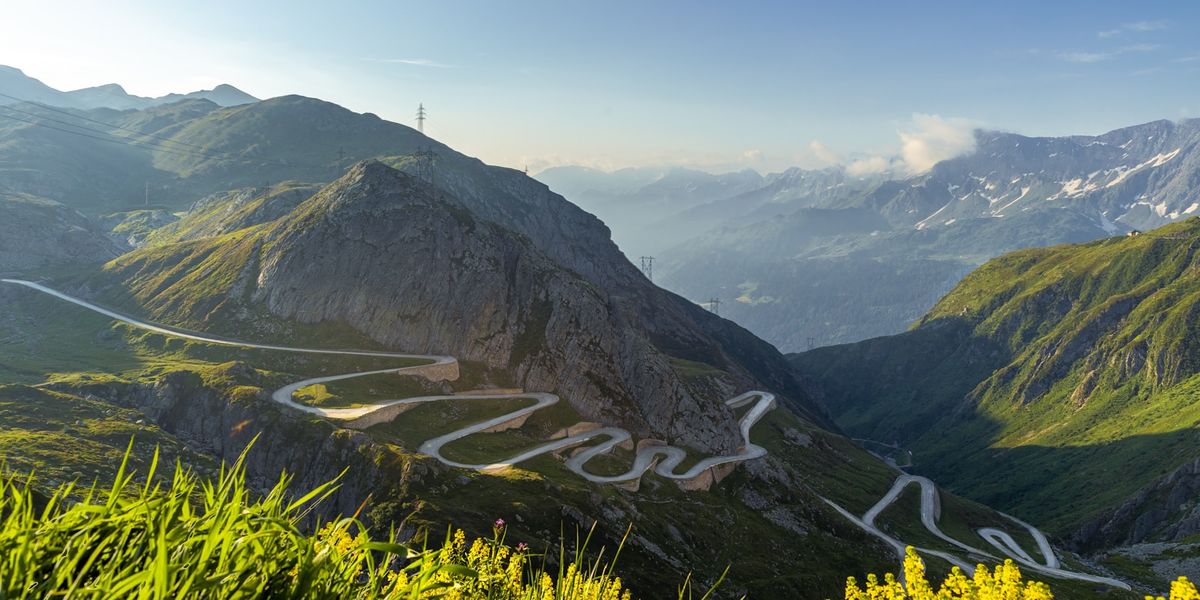 Alpine landscape with a winding road and distant snowy peaks in Switzerland
