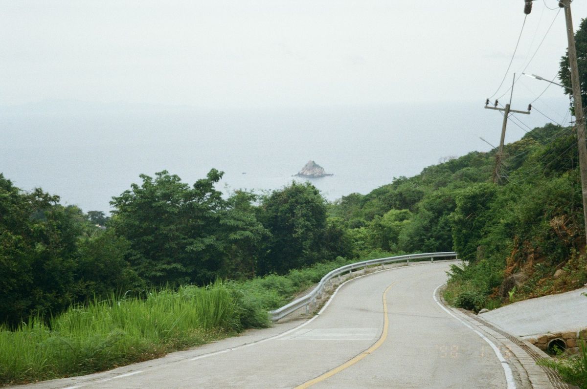 Winding coastal road through green hills overlooking sea Thailand