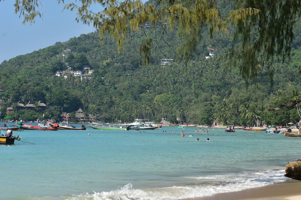 Boats anchored in tropical bay with lush green hills Thailand