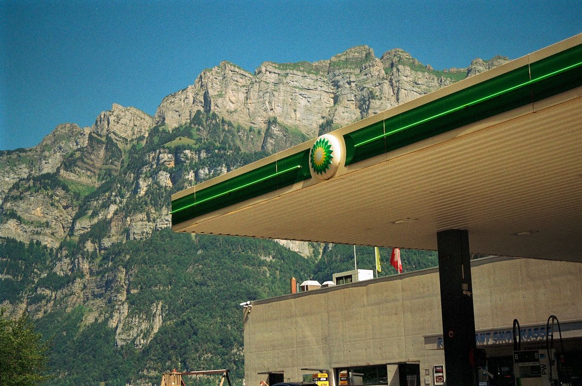 Gas station with fuel price signs and mountains in the background
