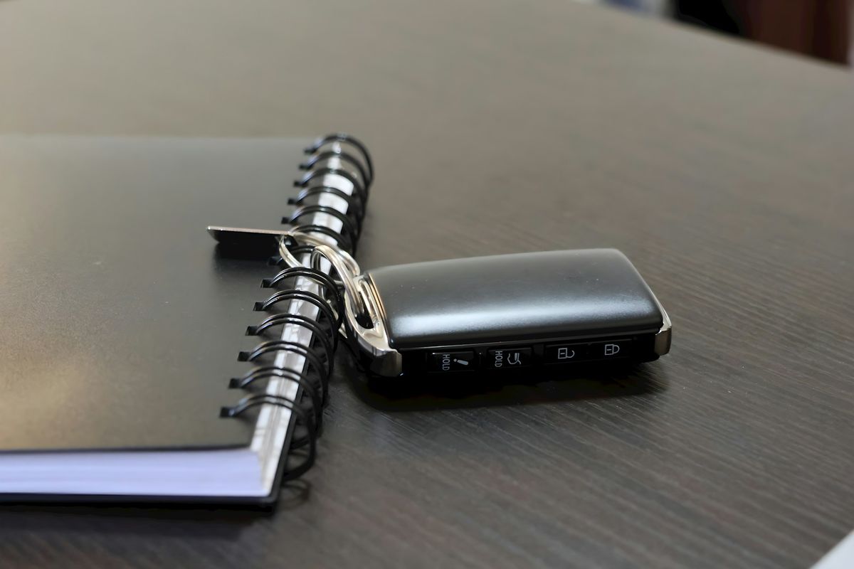 Car key resting next to a notebook, representing insurance paperwork