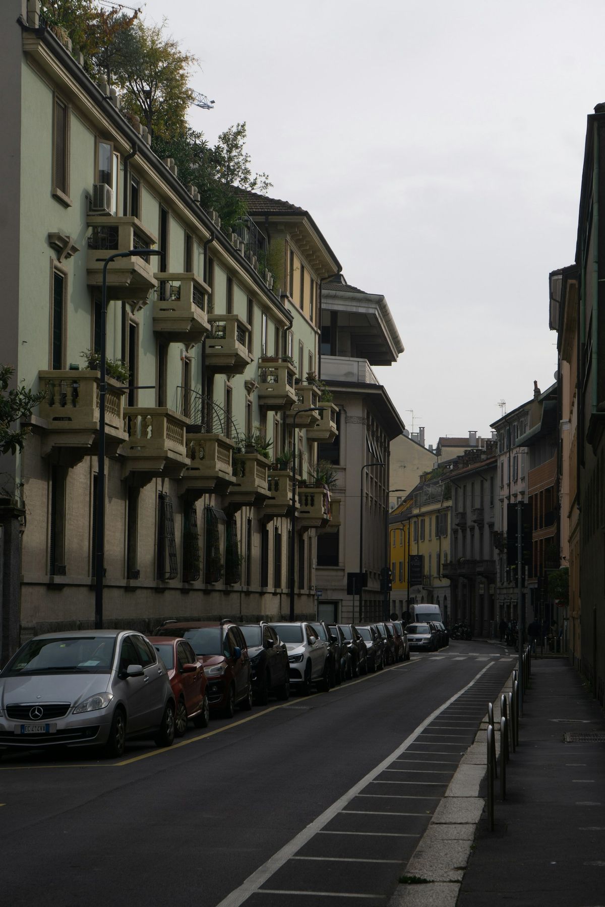 Street lined with parked cars and apartment buildings in a European city