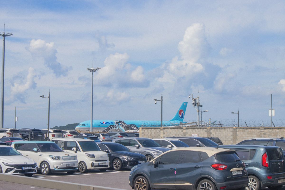 Rental cars parked with an airplane in the background at an airport