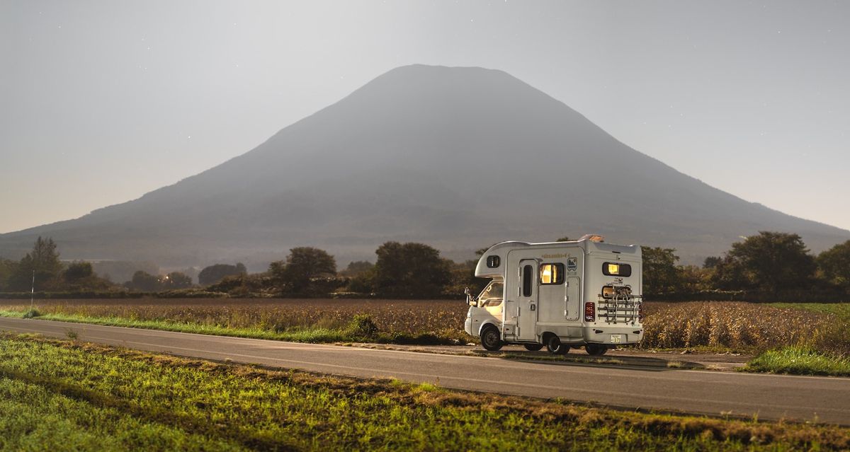 Camper van driving on a road with mountains in the background