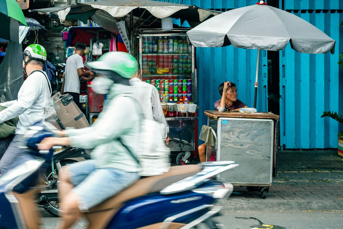 Scooters and a street vendor's cart on a busy Southeast Asian street