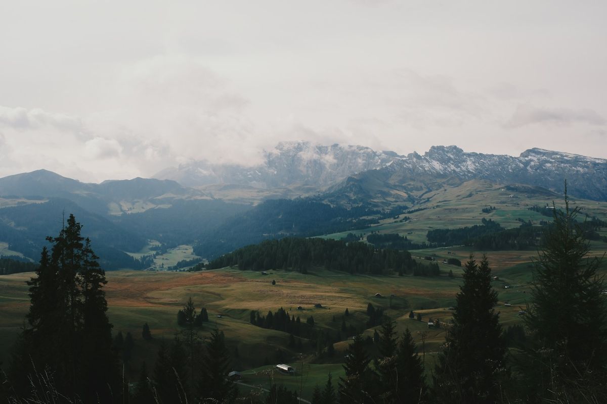 Snow-capped Dolomite peaks rising above rolling green meadows