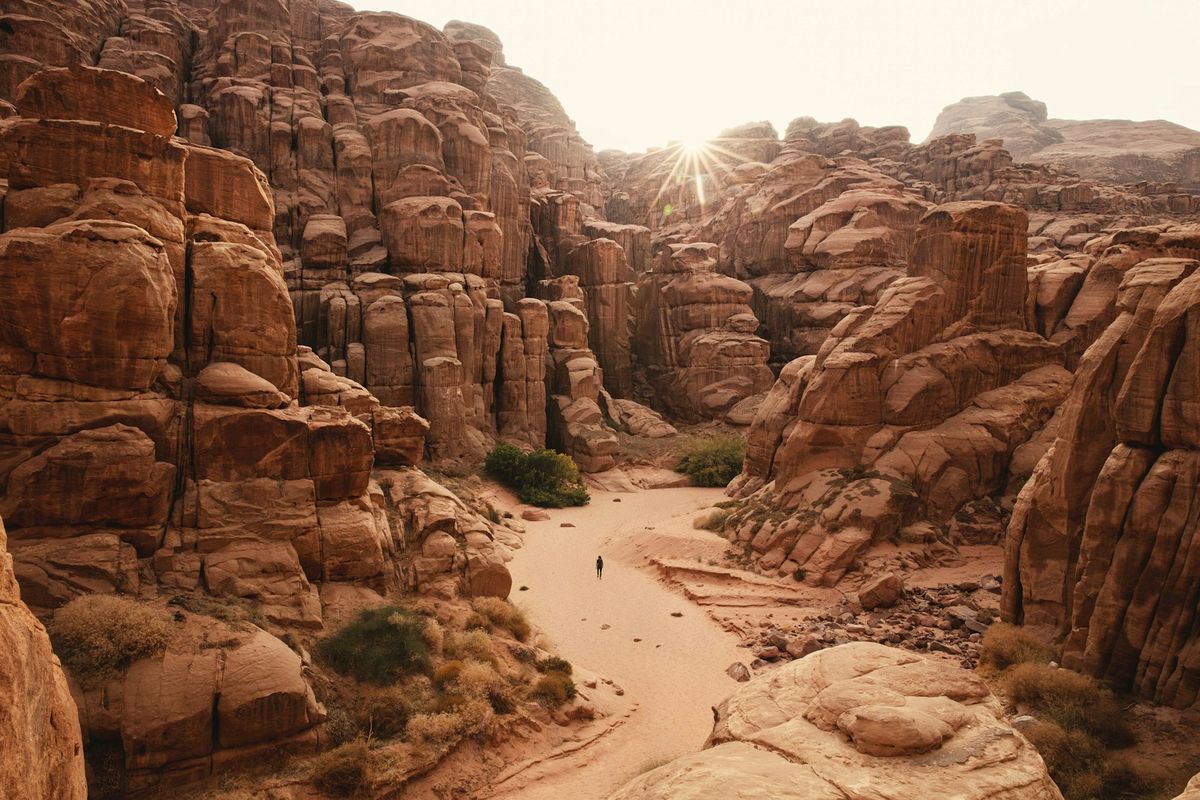 Person walking through the narrow Siq canyon passage leading to Petra