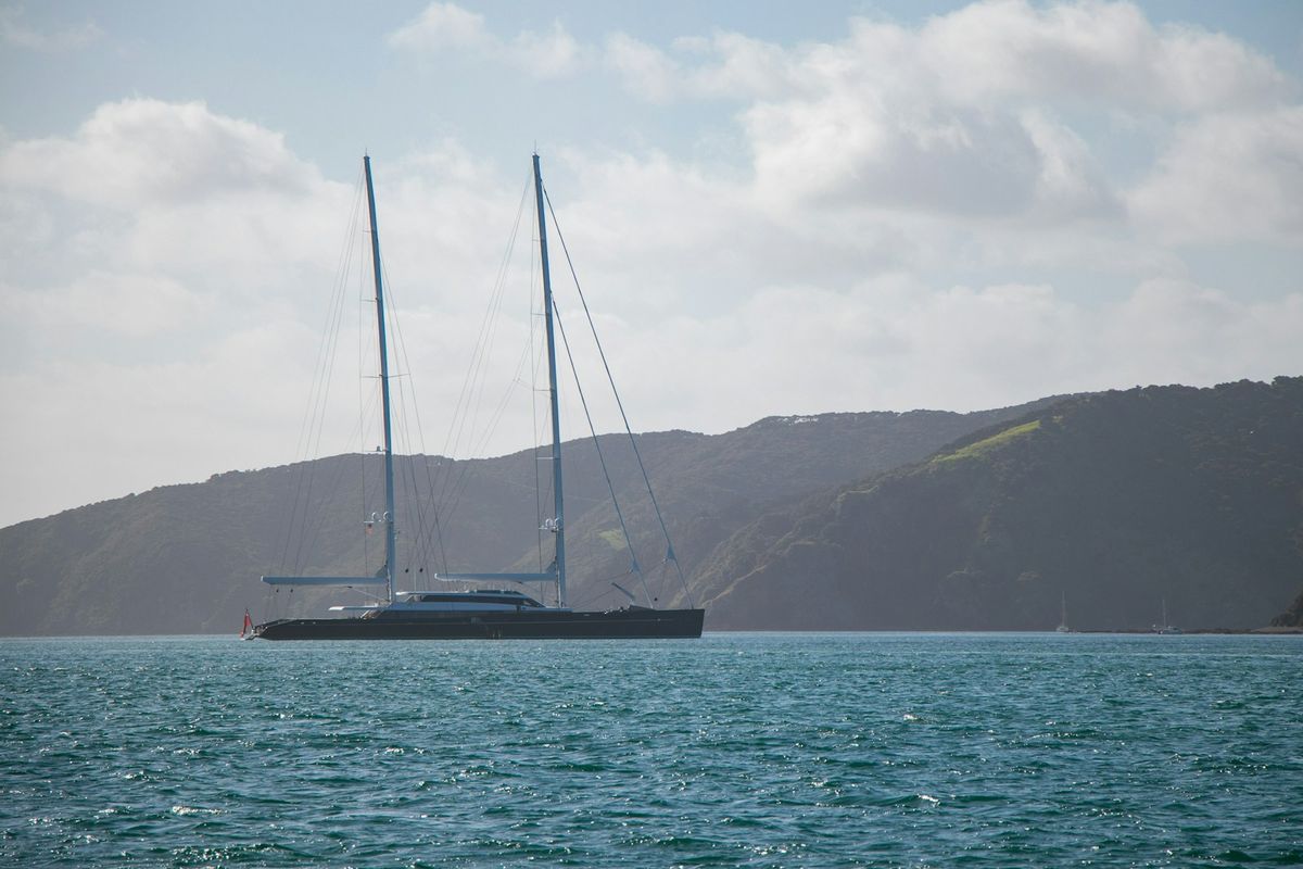 A white sailboat cruising the blue waters of the Bay of Islands, New Zealand