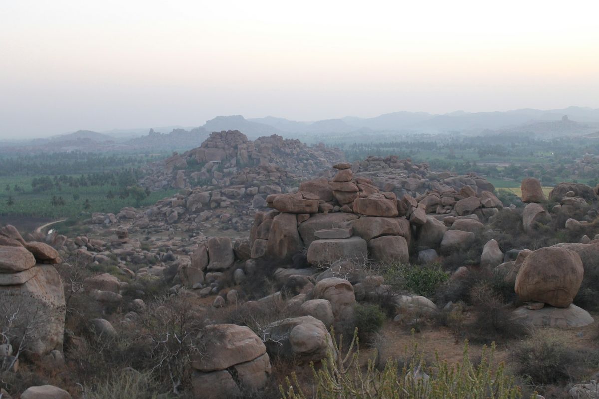 Stacked granite boulders on a green hillside at Hampi