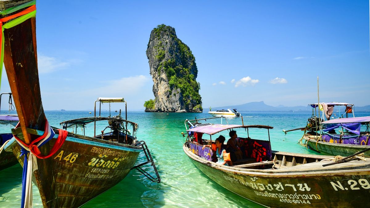 Longtail boats floating in clear turquoise water near a Thai island