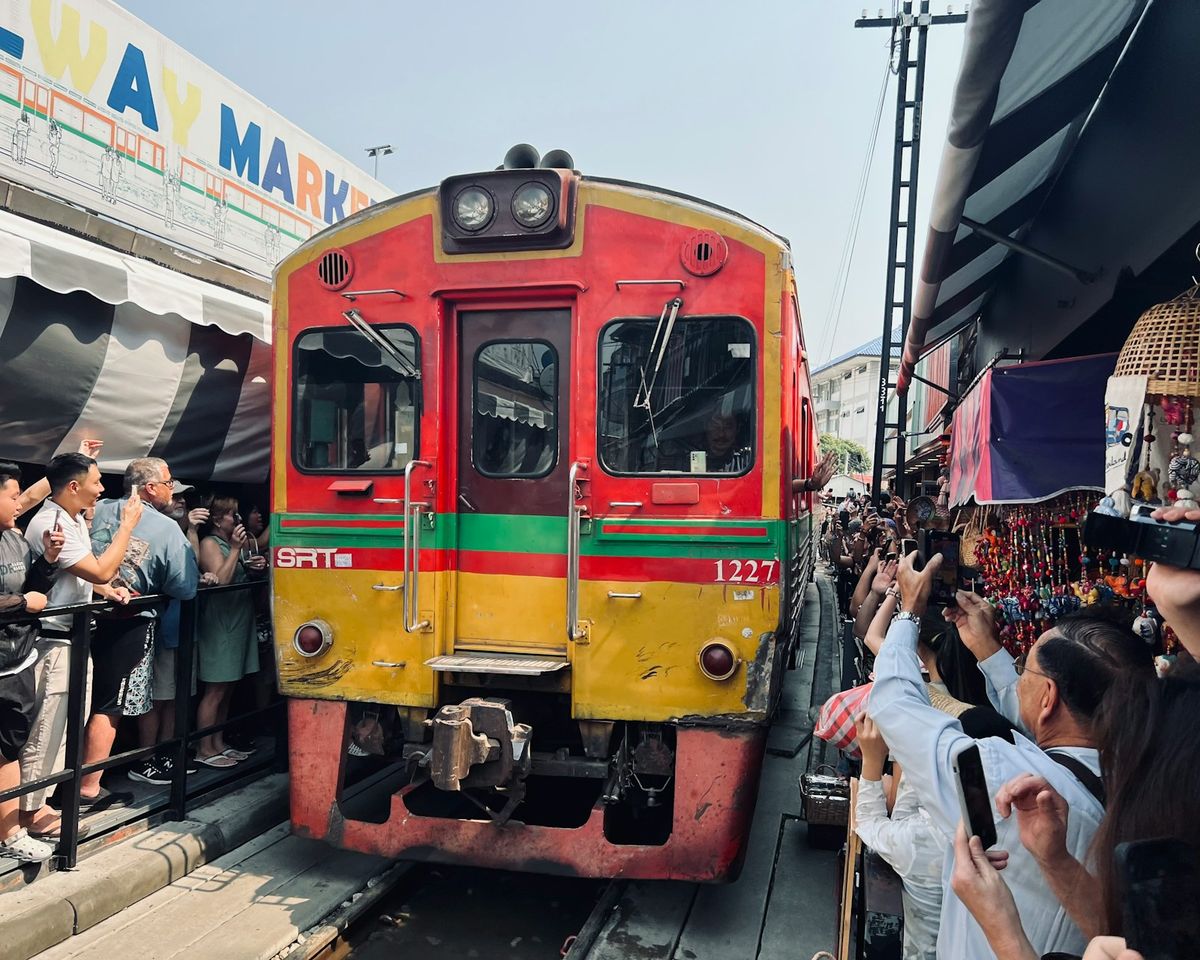 Train passing through the Maeklong railway market crowd
