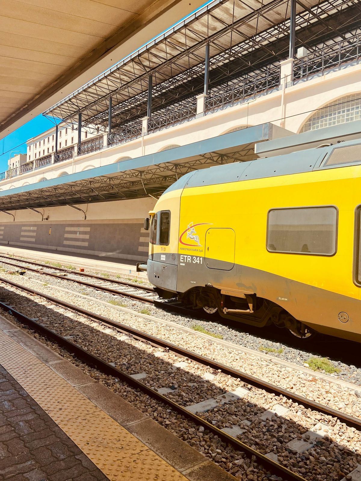 Yellow regional train at an Italian coastal station