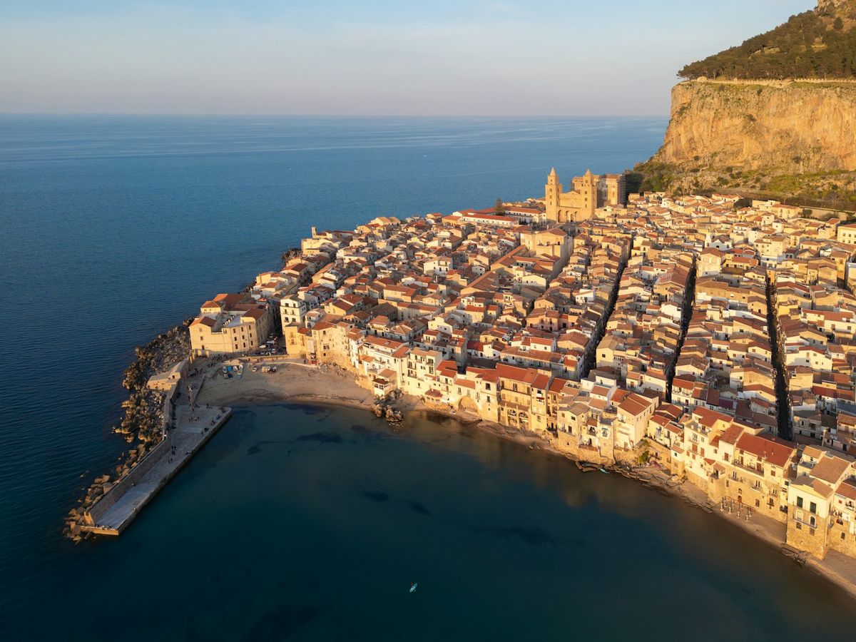 Sicilian coastal town with colourful buildings against cliff and sea
