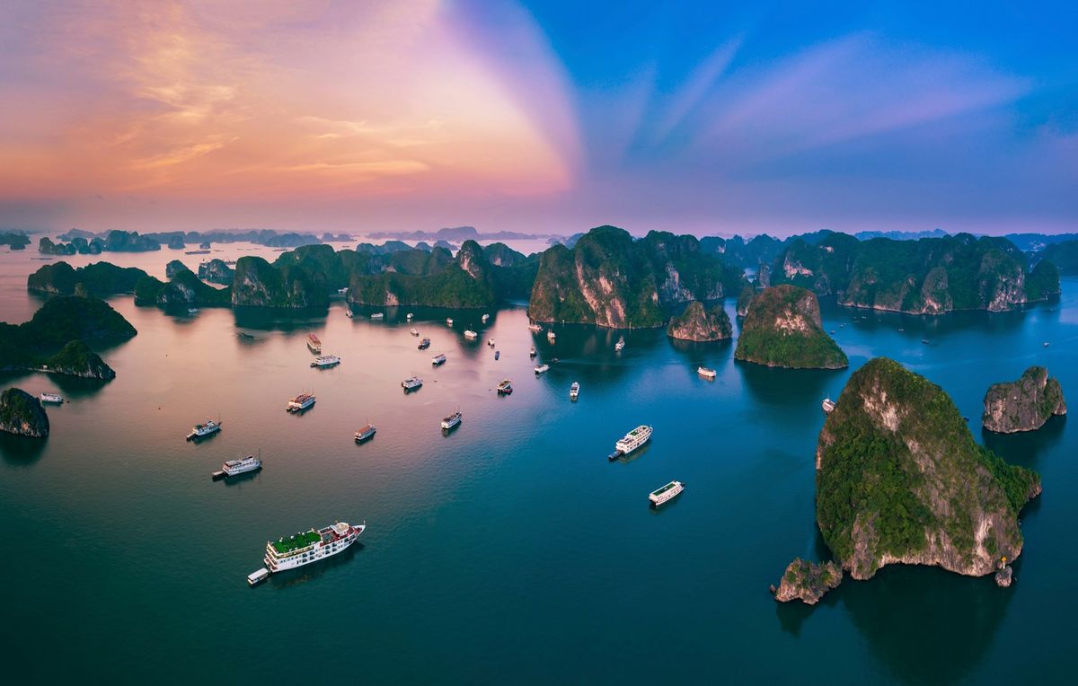 Limestone karst islands rising from calm water at sunset in Ha Long Bay Vietnam