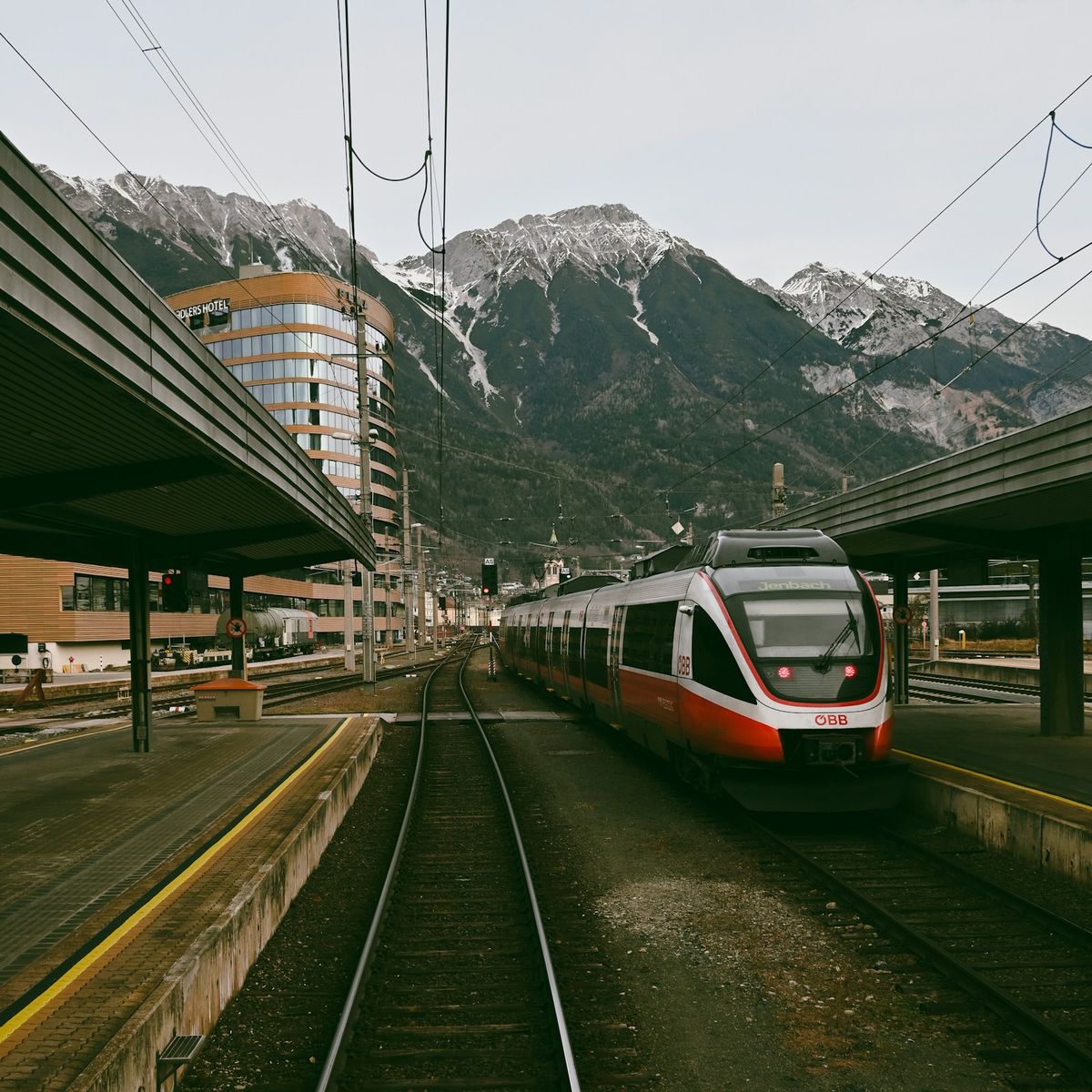 Modern train at alpine station with mountains in background