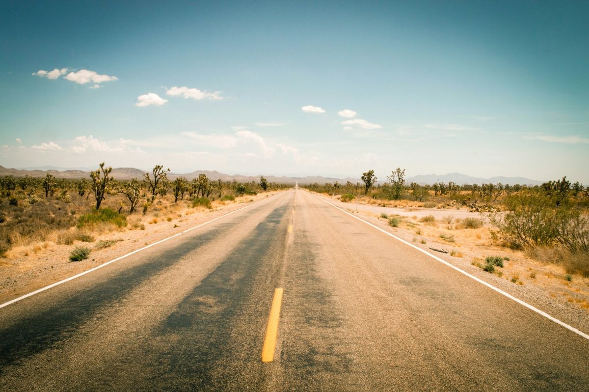 Empty desert highway leading toward distant mountains in Arizona